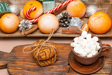 Oatmeal cookies and coffee with marshmallows on a Christmas table with citrus fruits. Close-up, selective focus