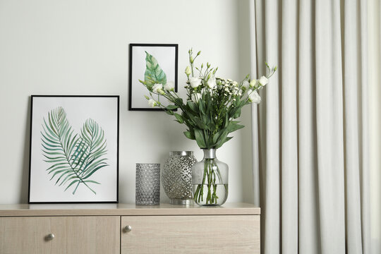 Decorative vases and pictures on commode indoors