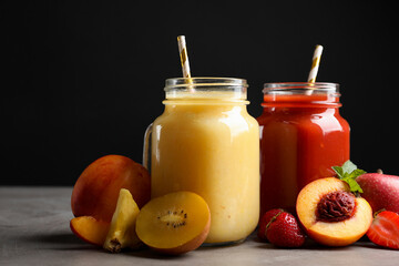 Delicious juices and fresh ingredients on grey table against black background