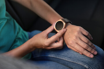 Woman using modern smart watch in car, closeup