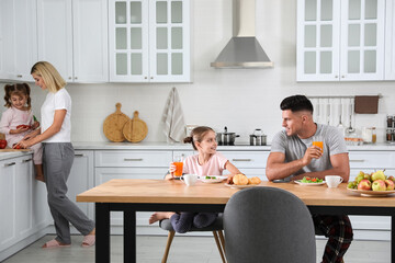 Happy family having breakfast together at table in modern kitchen