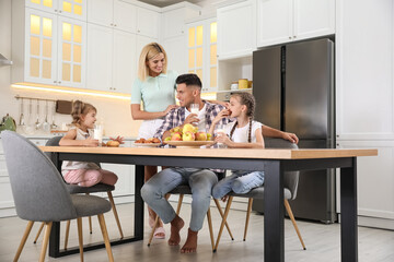 Happy family eating together at table in modern kitchen
