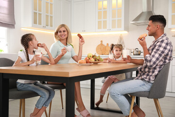 Happy family eating together at table in modern kitchen