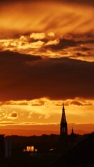 Fototapeta na wymiar Kirchturm im Sonnenuntergang mit Wolkenspiel in Abenddämmerung