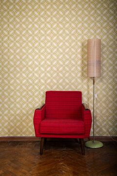 Vintage room with old fashioned armchair, standart lamp, old fashioned wallpaper and weathered wooden parquet floor
