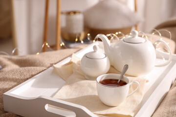 Fototapeta na wymiar White tray with ceramic tea set on bed
