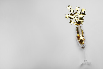 Flat lay composition with confetti and champagne glass on light background. Space for text