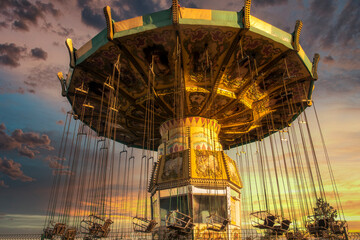 Swinging carousel roundabout chain ride at sunset