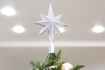 Silver star topper on Christmas tree indoors