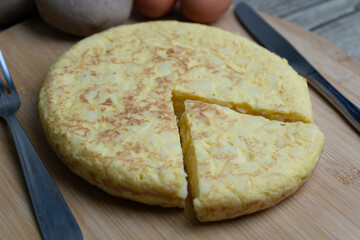 Sliced Spanish Potato omelette called Tortilla de patatas with eggs and potatoes on wooden board.Typical spanish food .Tapas background.