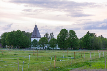 Meadows on the Outskirts of a Small swedish village with church in trees during beautiful sunset, countryside church
