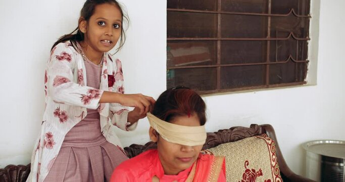 Slow-motion close-up CU portrait of a adult woman, single paren,  with her kids, son daughter, having fun playing games blindfolded at home hide and seek during lockdown quarantine 