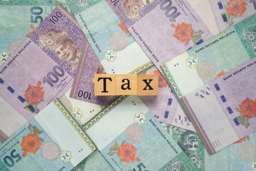 Text TAX on wooden cubes with a bundle of the banknote. Flat lay view concept.