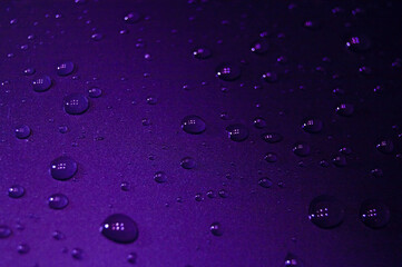 Fluorescent water drops on surface in dark colors concept