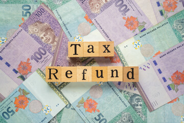 Text TAX REFUND on wooden cubes with a bundle of the banknote. Flat lay view concept.