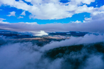 Foggy valley, fall season landscape, fields.  Fall season weather, drone flight through the clouds, aerial backdrop.