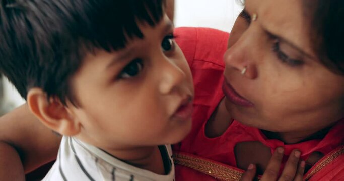 Slow-motion close-up portrait of a young boy child with her mother in traditional Indian clothes as they have fun hug bond together hold and have a good playful time