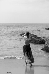 The girl from the back standing on the beach in black and white