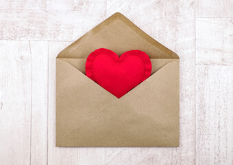 Red heart in an envelope on wooden background, delivery with love idea, top view.