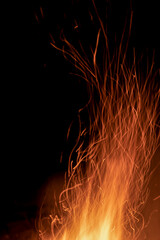Sparks from a fire against a dark night background. Bonfire. Vertical photo