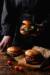 Chef in black uniform holding a burger, dark restaurant atmosphere