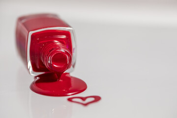An inverted bottle of spilled nail polish. Drawing heart on glass.