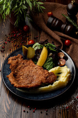 Austrian schnitzel with pickles and potato in a restaurant, top view