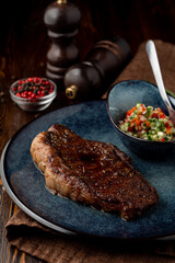 Juicy sirloin grilled and served with salad, dark restaurant photo
