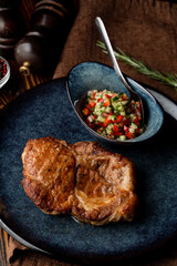 Roasted greasy pork steak in a blue clay craft dish, expensive restaurant photo
