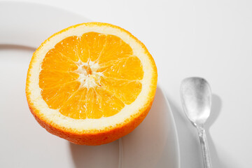 Arancia su piatto bianco e cucchiaino argento
