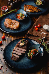 Different types of thick steaks on a wooden table
