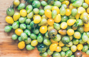 Yellow and green cocktail tomatoes on bamboo plate, close up