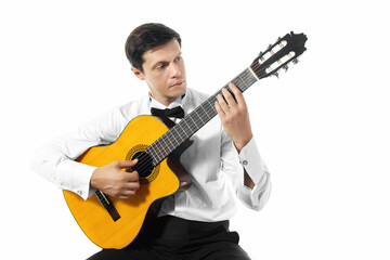 Young man in white shirt with bow tie posing with classical guitar in studio on white background.