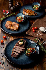 Different types of thick steaks on a wooden table