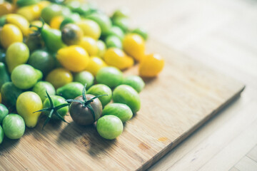 Yellow and green cocktail tomatoes on bamboo plate, close up