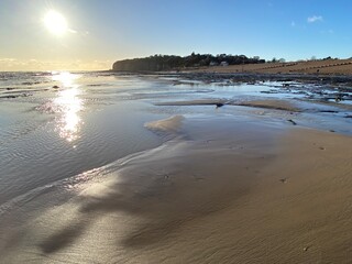 Pett Level Beach at Sunset. With pool of sea ocean water and rocks in foreground. Winchelsea Beach meets the cliffs a petrified forest visible at low tide, on the South coast of England East Sussex UK