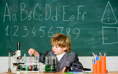 Knowledge concept. Boy near microscope and test tubes in school classroom. Kid study biology chemistry. Knowledge day. Basic knowledge primary school education. Happy childhood. Child enjoy studying