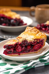 Piece of homemade cherry pie on a white plate close-up. Selective focus, dark background.