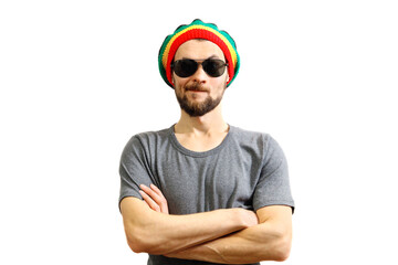 Young caucasian skeptic man in rasta hat, sunglasses and grey t-shirt on white background.