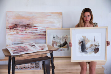 Modern art and lifestyle. Female artist showing her work in the studio. Portrait of young adult...