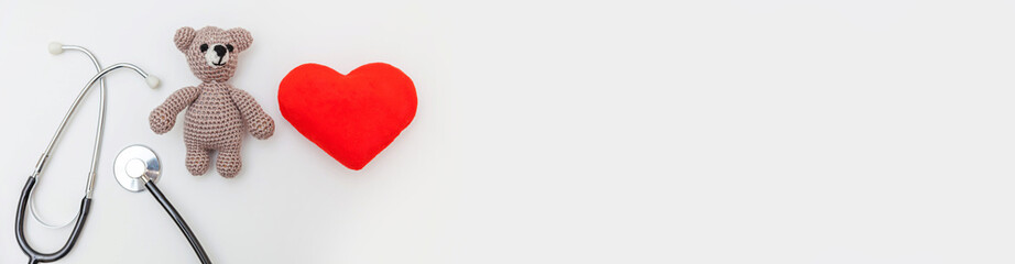 Simply minimal design toy bear red heart and medicine equipment stethoscope isolated on white background. Health care children doctor concept. Pediatrician symbol. Flat lay top view copy space. Banner