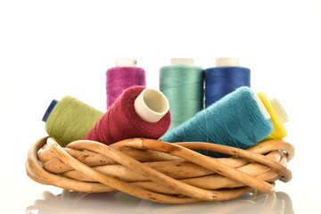 Several spool of colored thread with a wreath of vine, close-up, isolated on white.