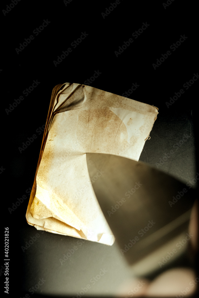 Poster a vertical shot of an old wethered dairy notebook with a sharp knife tip pointing on it