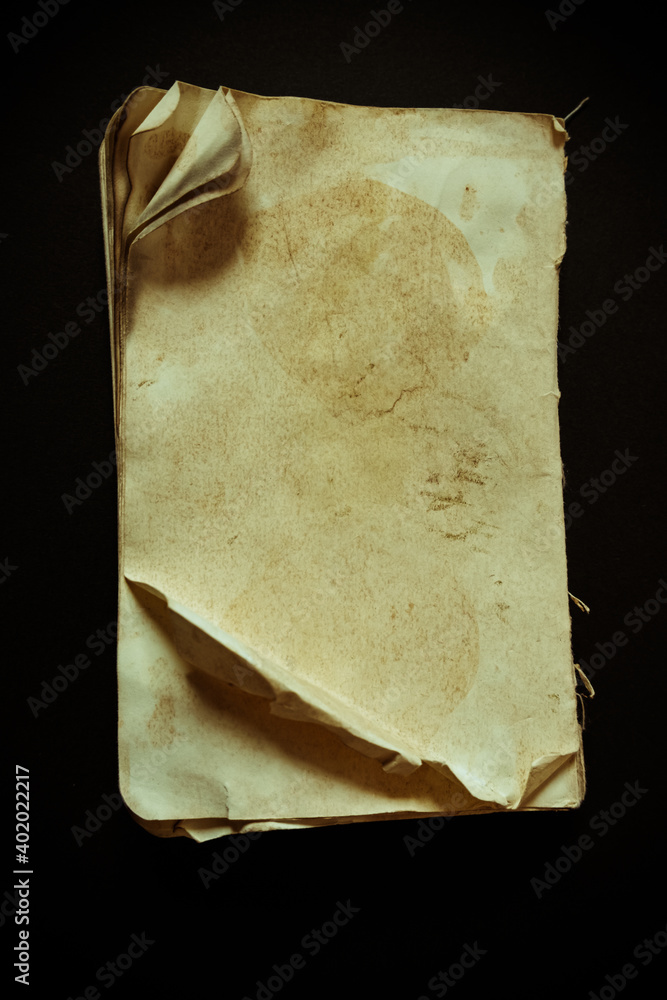 Poster a vertical shot of an old weathered blank paper diary notebook isolated on a black background