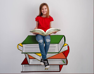 Little girl reading sitting on books stack