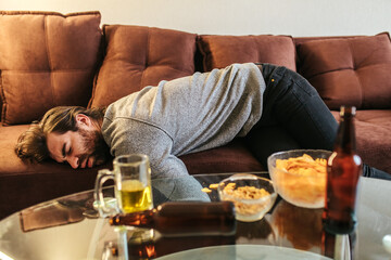 man sleeping on sofa after party at home. Morning hangover after party. Celebrating holiday. He is...