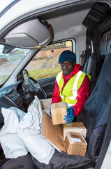 Hampshire, England, UK. 2020, Male courier delivering parcels and packages during Covid-19 epidemic...