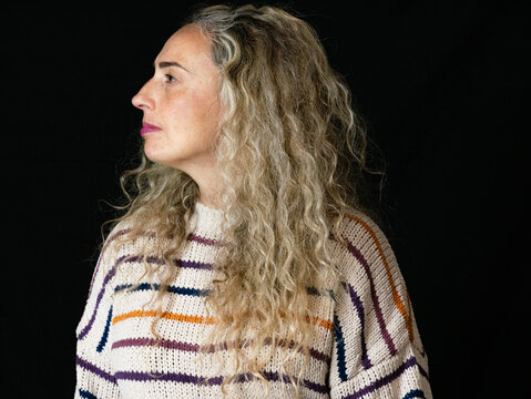 A closeup shot of a beautiful blonde curly-haired female on the black background