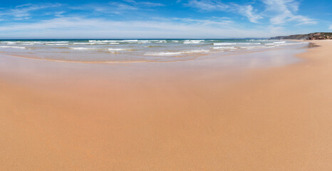 sandy Bordeira beach with smooth surface, ocean with waves at the horizon, West algarve portugal
