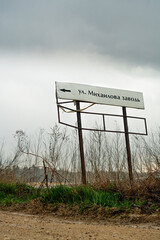 Road sign 'Mikhaylova Zavod' St.' during rain